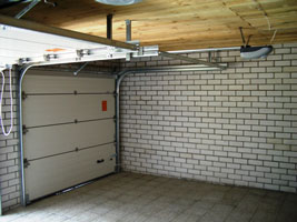 Секционные ворота, установленные в гараже с кирпичными стенами